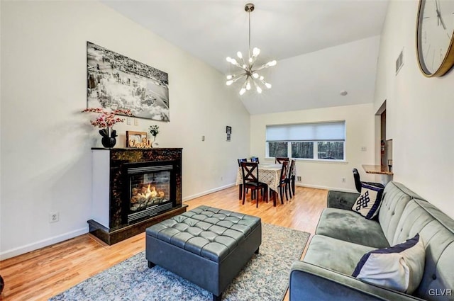 living room with a premium fireplace, hardwood / wood-style floors, vaulted ceiling, and a chandelier