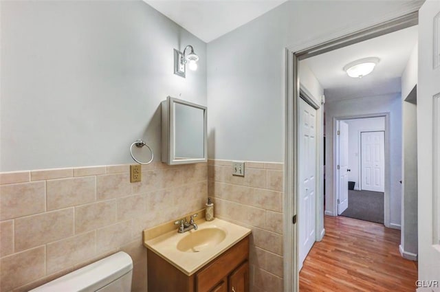 bathroom with toilet, hardwood / wood-style floors, tile walls, and vanity