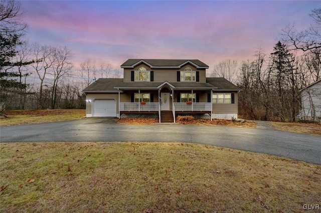 view of front of house featuring a porch, a lawn, and a garage