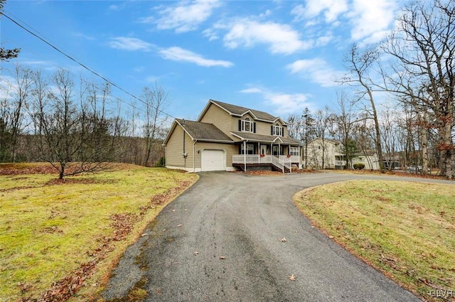 view of front of property featuring covered porch, a front yard, and a garage