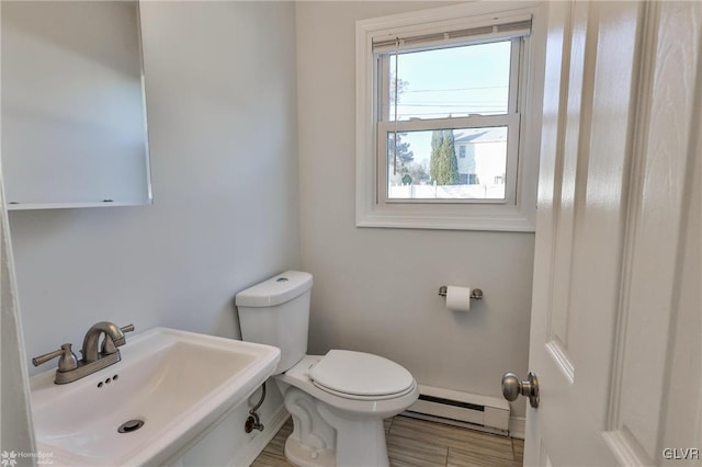 bathroom with toilet, a baseboard heating unit, and sink