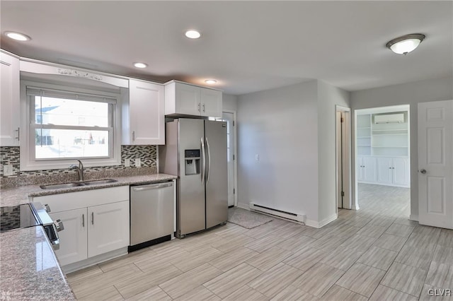 kitchen featuring light stone counters, stainless steel appliances, baseboard heating, white cabinetry, and sink