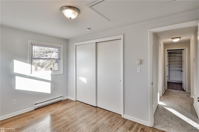 unfurnished bedroom featuring baseboard heating, a closet, and light hardwood / wood-style flooring