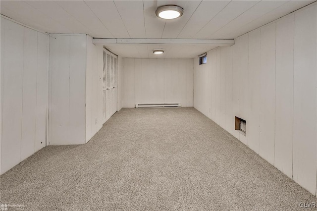 basement with baseboard heating, wood walls, and light colored carpet