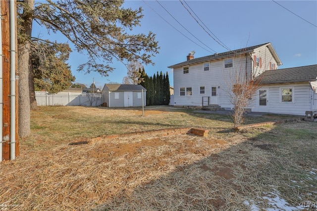 back of house featuring a storage unit and a yard