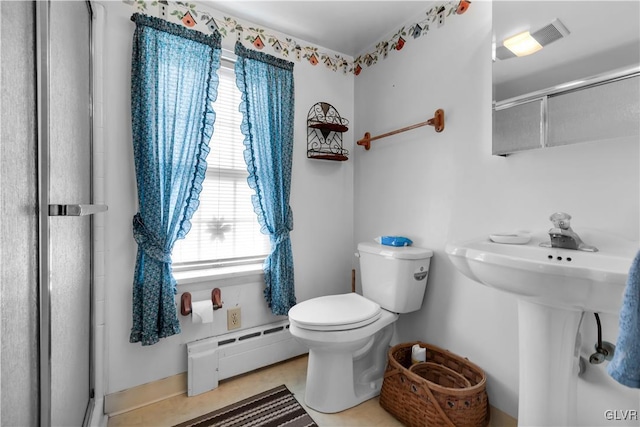 bathroom with toilet, tile patterned floors, baseboard heating, and a shower with shower door