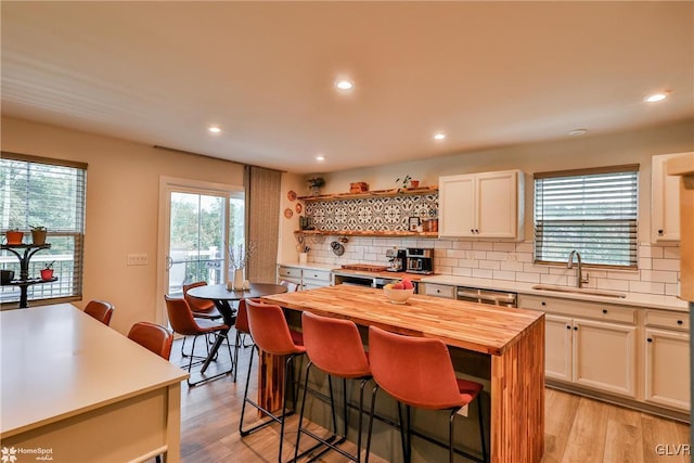 kitchen with tasteful backsplash, a kitchen island, butcher block countertops, a kitchen breakfast bar, and sink