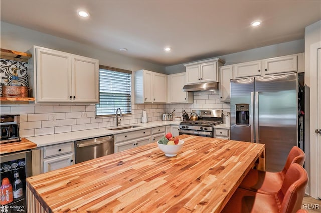 kitchen featuring appliances with stainless steel finishes, wooden counters, white cabinetry, and sink