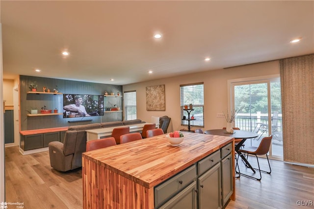 kitchen featuring light wood-type flooring, butcher block countertops, gray cabinetry, and a center island