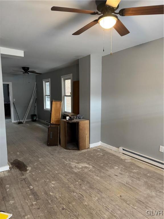 unfurnished living room with a baseboard heating unit and hardwood / wood-style flooring