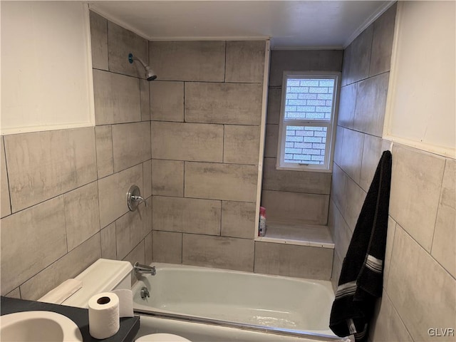 bathroom with toilet, tile walls, ornamental molding, and tiled shower / bath