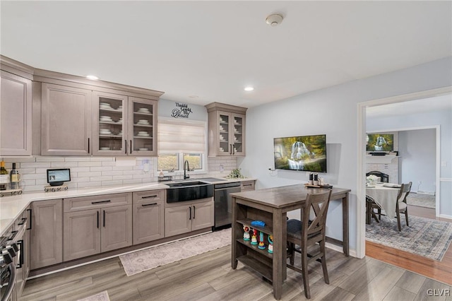 kitchen featuring light hardwood / wood-style floors, tasteful backsplash, stainless steel dishwasher, and sink