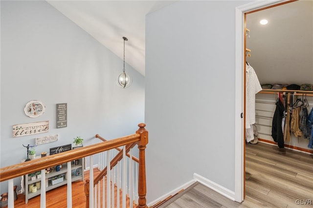 stairs featuring lofted ceiling, an inviting chandelier, and hardwood / wood-style floors