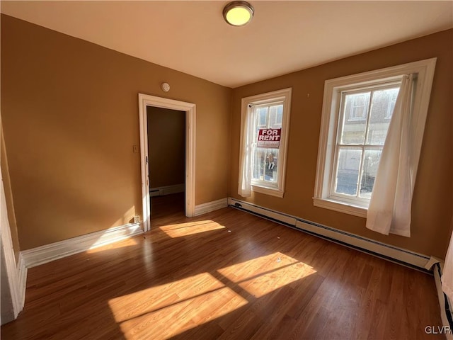 unfurnished room featuring baseboard heating and dark wood-type flooring