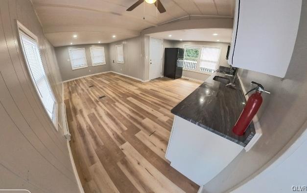 kitchen featuring white cabinetry, ceiling fan, vaulted ceiling, light hardwood / wood-style flooring, and sink