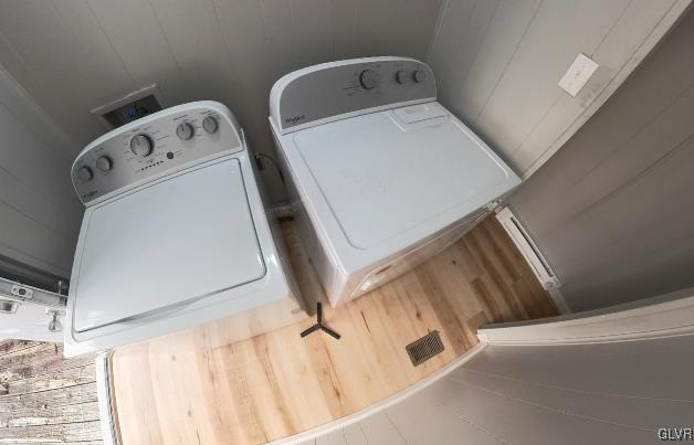 washroom with independent washer and dryer and wooden walls