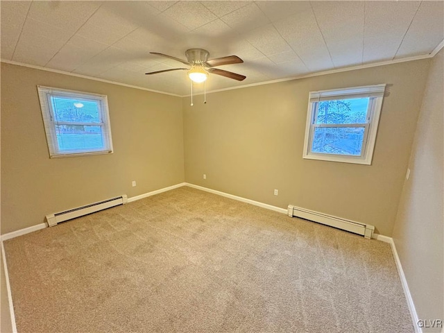 carpeted spare room featuring baseboard heating, crown molding, plenty of natural light, and ceiling fan