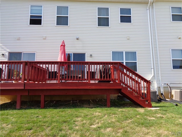 back of property featuring a wooden deck, cooling unit, and a lawn