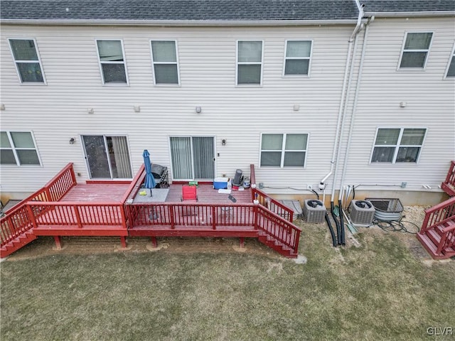 back of property with a wooden deck, a yard, and central air condition unit