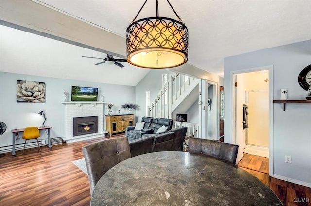 dining room with ceiling fan, lofted ceiling, a baseboard heating unit, a fireplace, and wood-type flooring