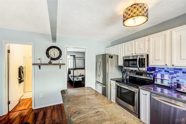 kitchen featuring dark hardwood / wood-style floors, beam ceiling, decorative backsplash, white cabinetry, and appliances with stainless steel finishes