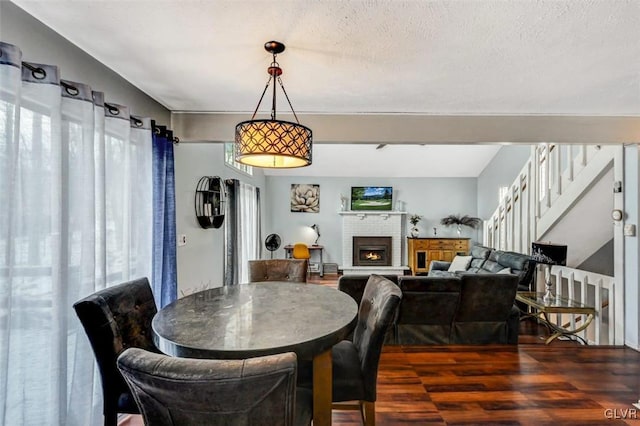 dining space with a brick fireplace, a textured ceiling, dark hardwood / wood-style floors, and a wealth of natural light