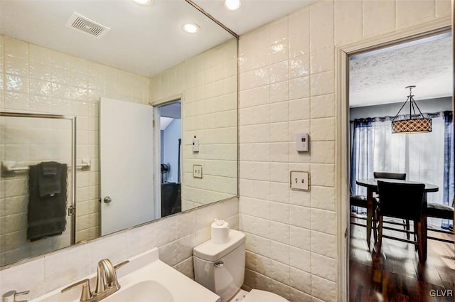 bathroom featuring a textured ceiling, toilet, tile walls, and vanity