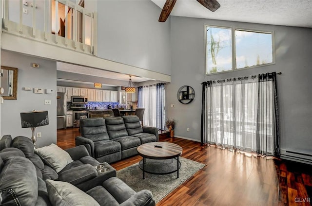 living room with ceiling fan, a healthy amount of sunlight, beamed ceiling, and a high ceiling