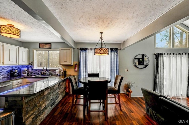 dining area with dark wood-type flooring, sink, and a textured ceiling