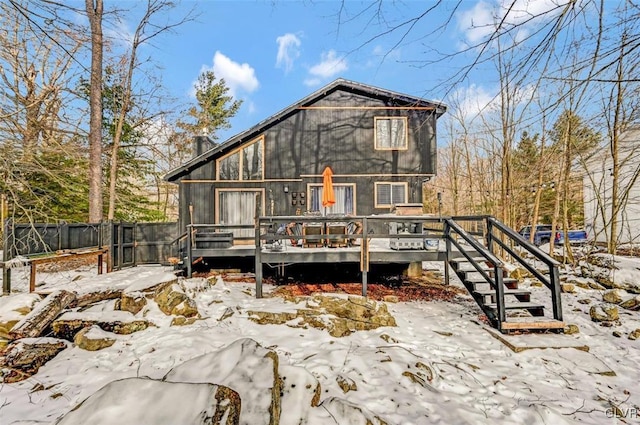 snow covered back of property featuring a wooden deck