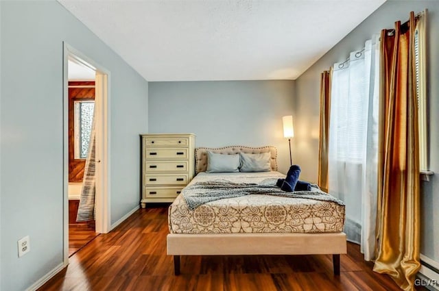 bedroom featuring dark wood-type flooring and ensuite bath