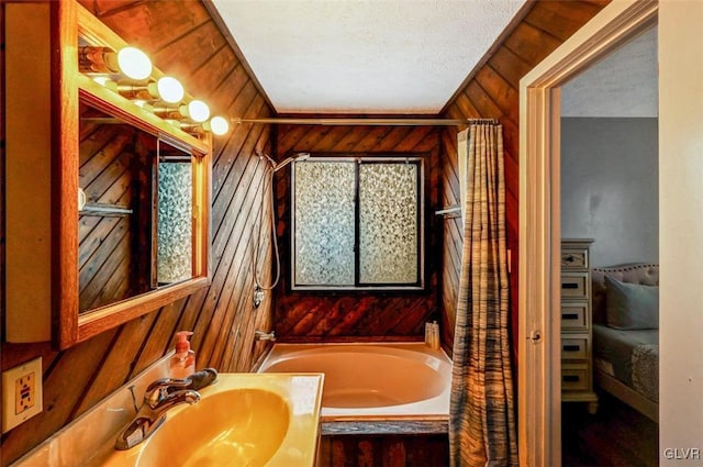 bathroom featuring a textured ceiling, a tub to relax in, vanity, and wood walls