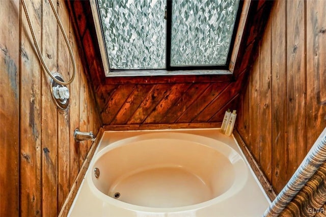 bathroom featuring a washtub and wooden walls