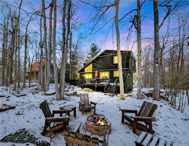 yard covered in snow with a wooden deck and a fire pit