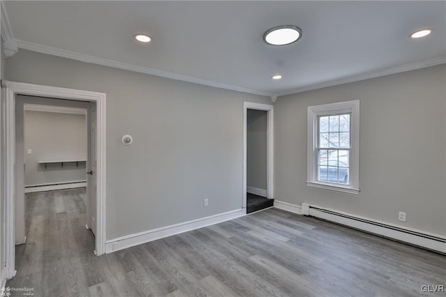 spare room with light hardwood / wood-style floors, a baseboard radiator, and crown molding