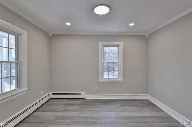 spare room featuring light hardwood / wood-style floors, baseboard heating, and ornamental molding