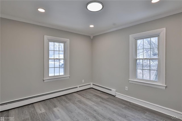 empty room featuring light wood-type flooring, baseboard heating, and crown molding