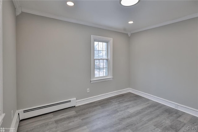 spare room featuring a baseboard heating unit, crown molding, and hardwood / wood-style flooring