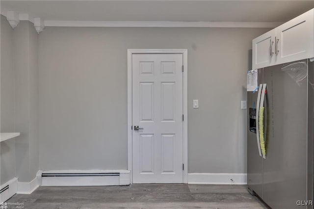 interior space featuring baseboard heating, crown molding, and hardwood / wood-style floors