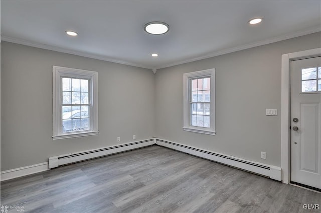 foyer with a baseboard heating unit, a wealth of natural light, and light hardwood / wood-style floors