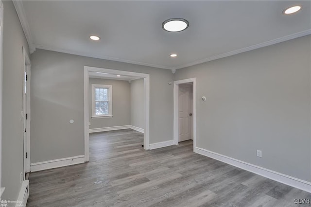 spare room featuring light wood-type flooring, crown molding, and a baseboard heating unit