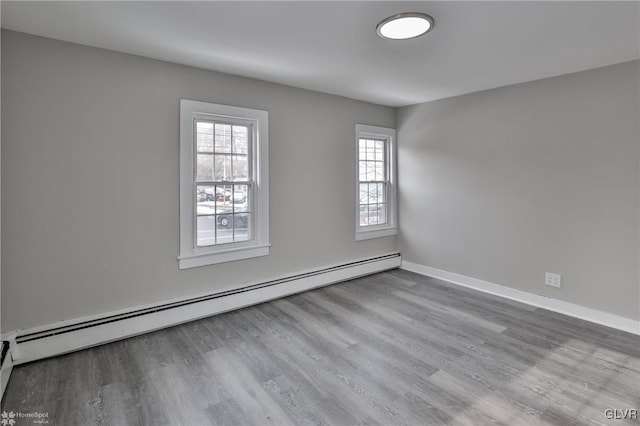 unfurnished room with a baseboard heating unit and hardwood / wood-style floors