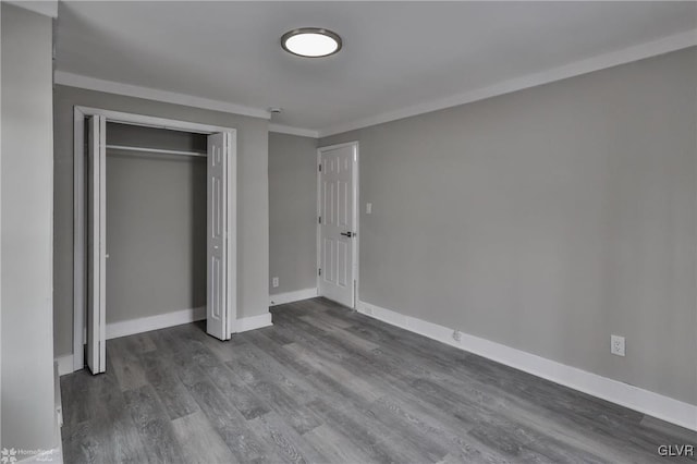 unfurnished bedroom featuring a closet, dark hardwood / wood-style flooring, and ornamental molding