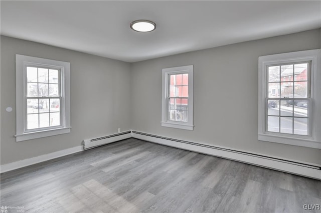 unfurnished room featuring a baseboard radiator, light hardwood / wood-style flooring, and a healthy amount of sunlight