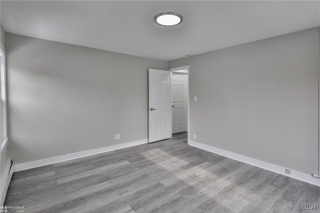 spare room with hardwood / wood-style floors and a baseboard heating unit