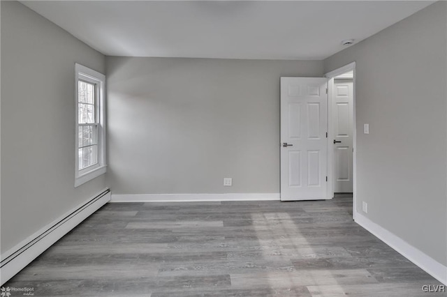 spare room featuring baseboard heating and hardwood / wood-style floors