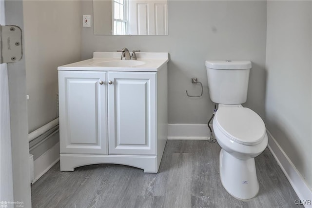 bathroom with toilet, vanity, and wood-type flooring