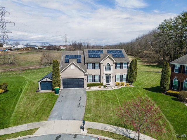 view of front of property featuring a garage, a front lawn, and solar panels