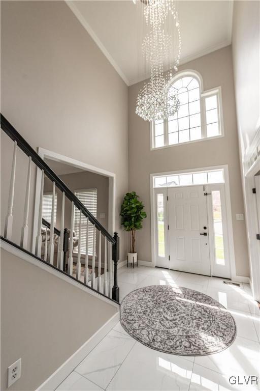 entrance foyer featuring plenty of natural light, a high ceiling, ornamental molding, and a chandelier