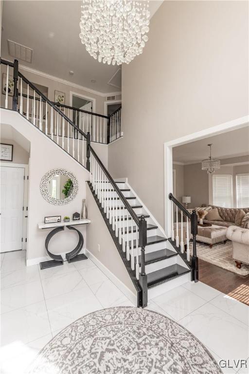 staircase featuring a notable chandelier, a high ceiling, and ornamental molding